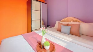 A hotel room with a bed, a sofa, a wardrobe, and a tray with flowers and a plant.