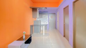 A hallway with a modern kitchen area, a small table with a vase, and a door on the right.