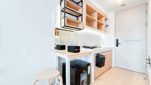 Eine kleine Küche mit einem integrierten Kühlschrank, einer Spüle und einer Arbeitsplatte mit Wasserspender.