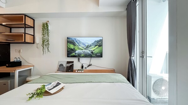 Une chambre d’hôtel moderne équipée d’un lit, d’un bureau, d’une télévision et d’une fenêtre avec des rideaux.