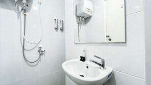 A modern bathroom with white tiles, a built-in sink, a handheld showerhead, and a wall-mounted mirror. - Cozy and Classical Studio Apartment Tokyo Riverside PIK 2 (Teluknaga)