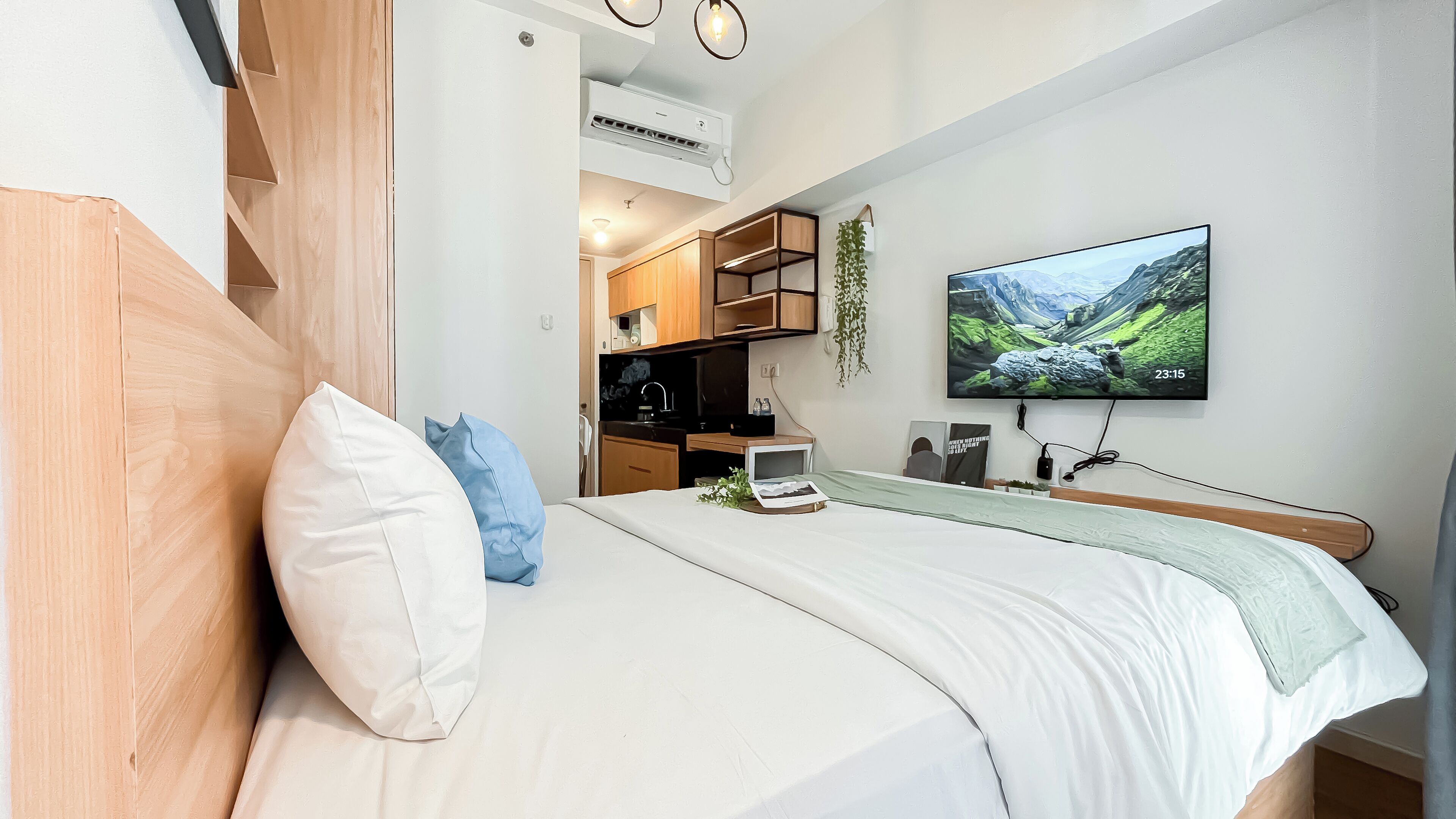 Una camera da letto moderna con un letto, una TV e angolo cottura.