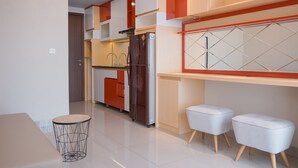 Una cucina moderna con frigorifero, lavandino e mobili arancioni. Ci sono due sgabelli bianchi e un tavolo rotondo con base a filo metallico.