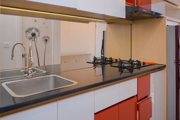 A modern kitchen with a stainless steel sink, gas stove, and red cabinetry.