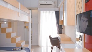 Una moderna camera d'albergo con un letto a castello, una scrivania con sedia, un televisore a schermo piatto e un'ampia finestra con tende.