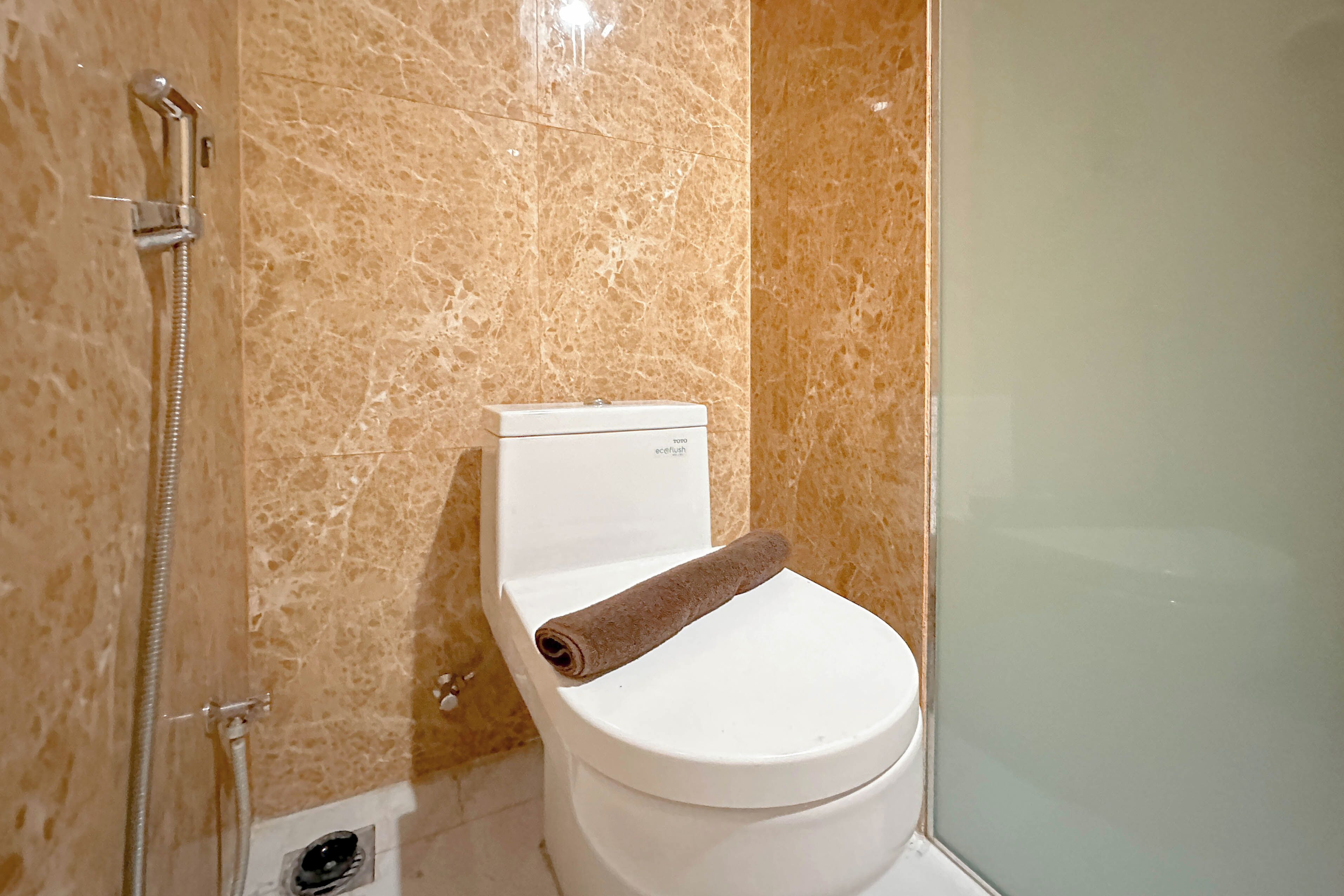A bathroom with a toilet, a shower, and a marble wall.