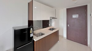 A modern kitchen with a refrigerator, sink, and stove. - Tidy and Strategic Location Studio Grand Sungkono Lagoon Apartment (Surabaya)