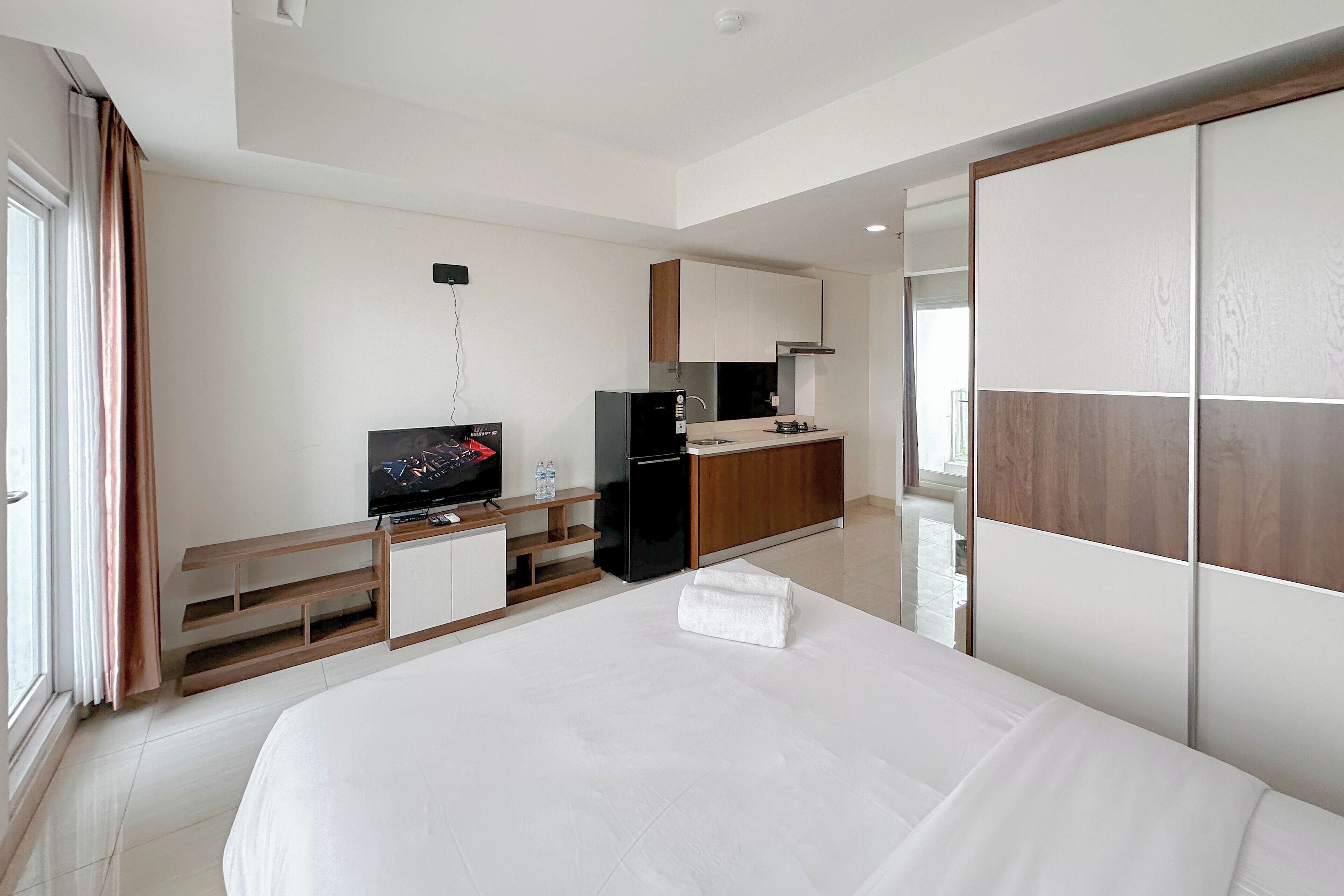 Une chambre d’hôtel moderne dotée d’un grand lit, d’une télévision, d’une kitchenette et d’un placard avec porte coulissante.