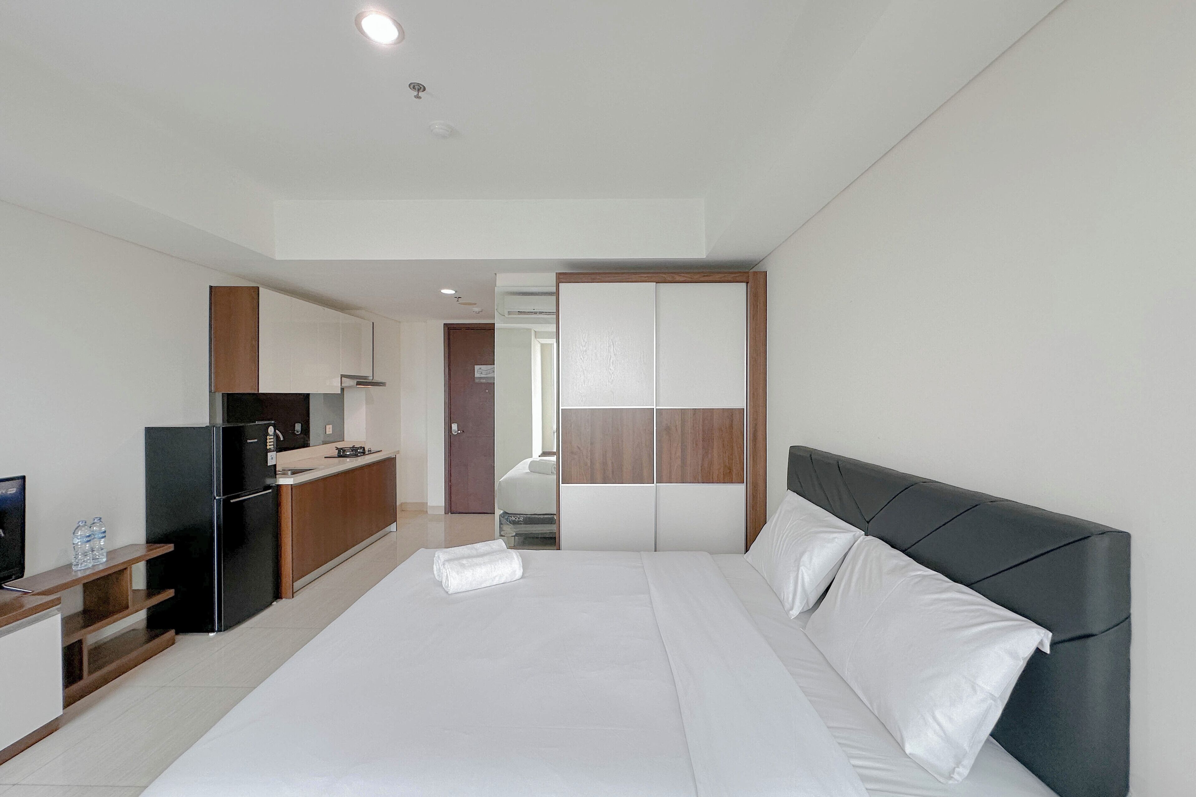 Et moderne hotelværelse med en stor seng, et indbygget skrivebord og et tekøkken.