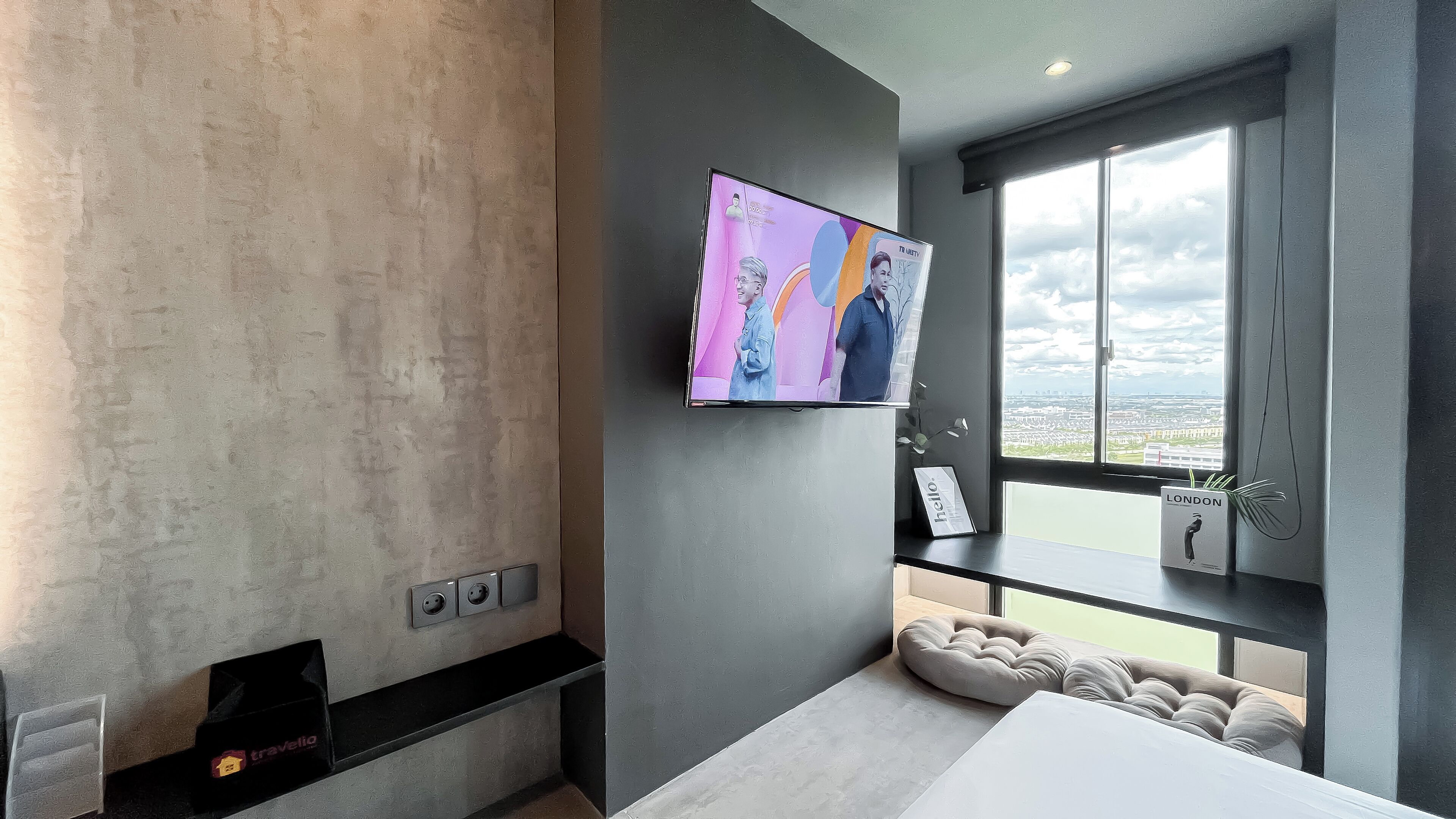Ein modernes Hotelzimmer mit großem Fenster und Blick auf die Stadt, einem flachbildfernseher an der Wand und einem eingebauten Kamin.