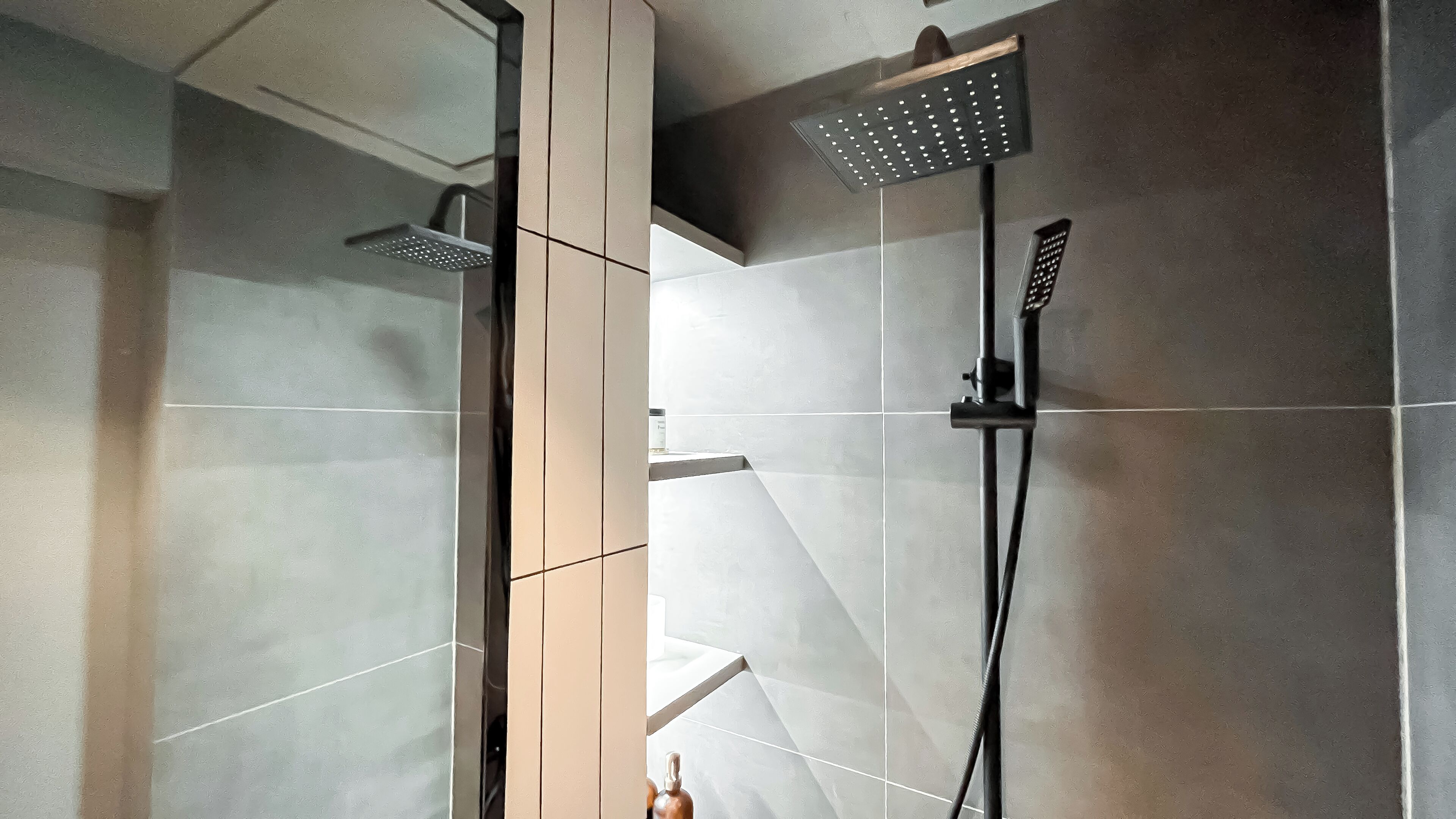 A modern shower with a handheld showerhead and a fixed wall-mounted showerhead.