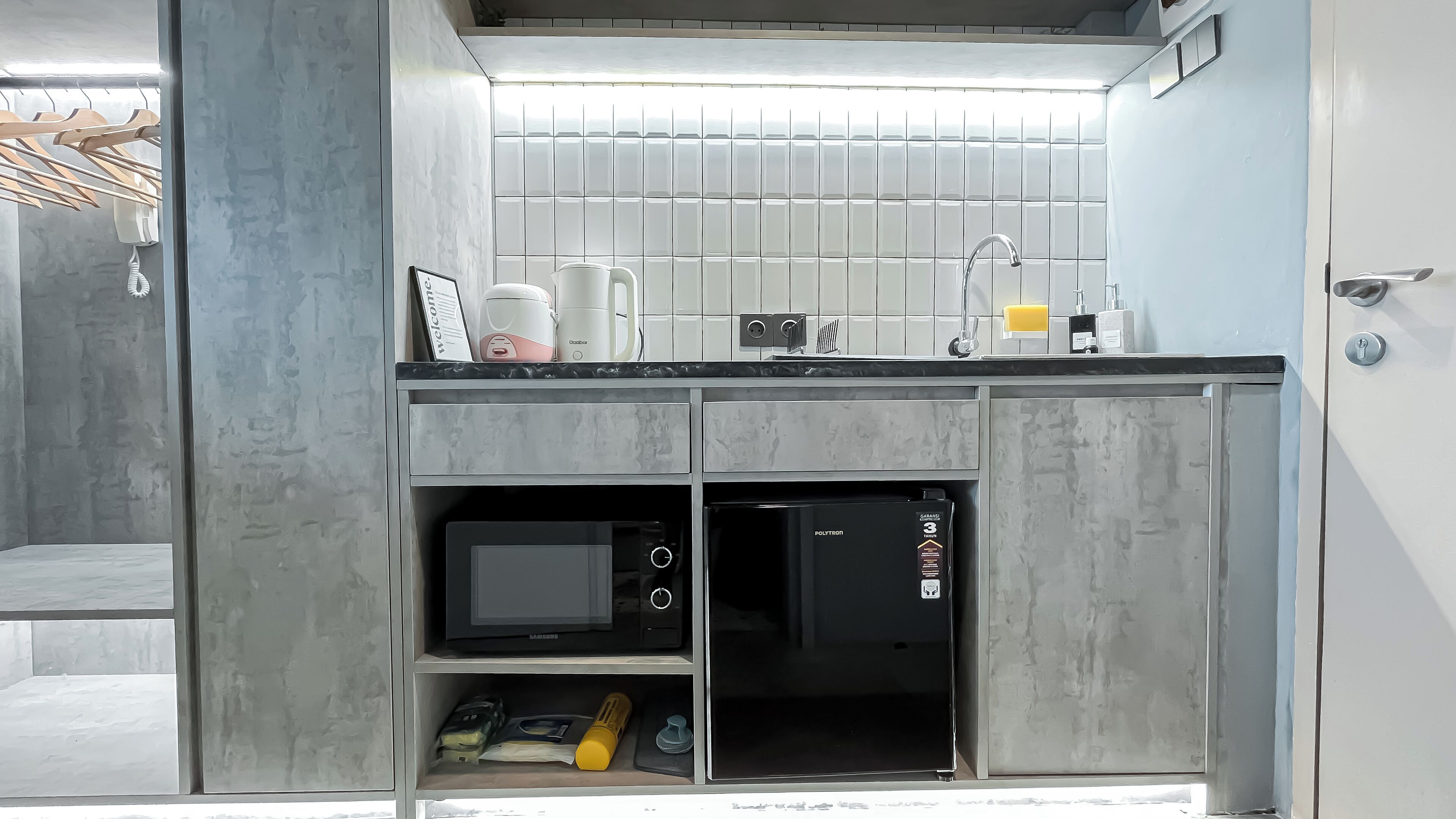 Una cucina moderna dotata di forno a microonde, macchina del caffè e piccolo frigorifero.