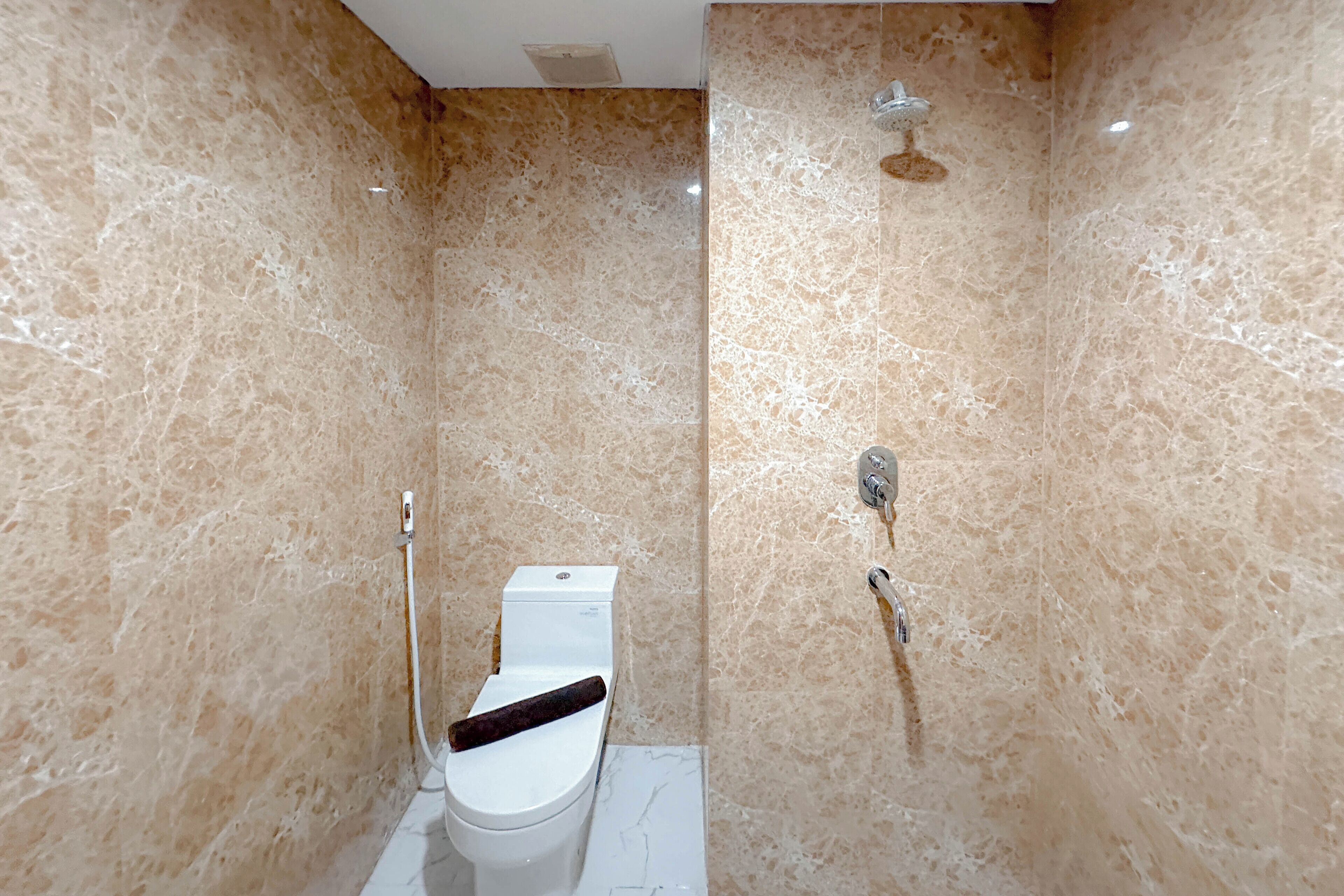 Une salle de bain avec des toilettes, une douche et des murs en marbre.