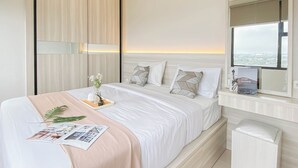 A modern hotel room with a large bed, a bedside table with a book, and a window with a city view.