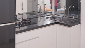 Una cocina moderna con encimera negra, electrodomésticos de acero inoxidable y armarios blancos.