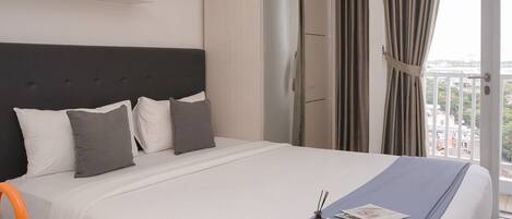 A hotel room with a bed, a wardrobe, a window with curtains, and a balcony view.