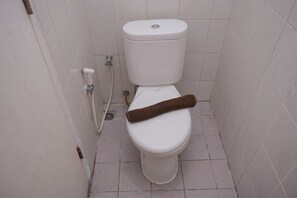A toilet with a towel placed on the seat, a visible pipe, and a drain in the floor. - Comfortable and Warm Studio at Poris 88 Apartment (Tangerang)