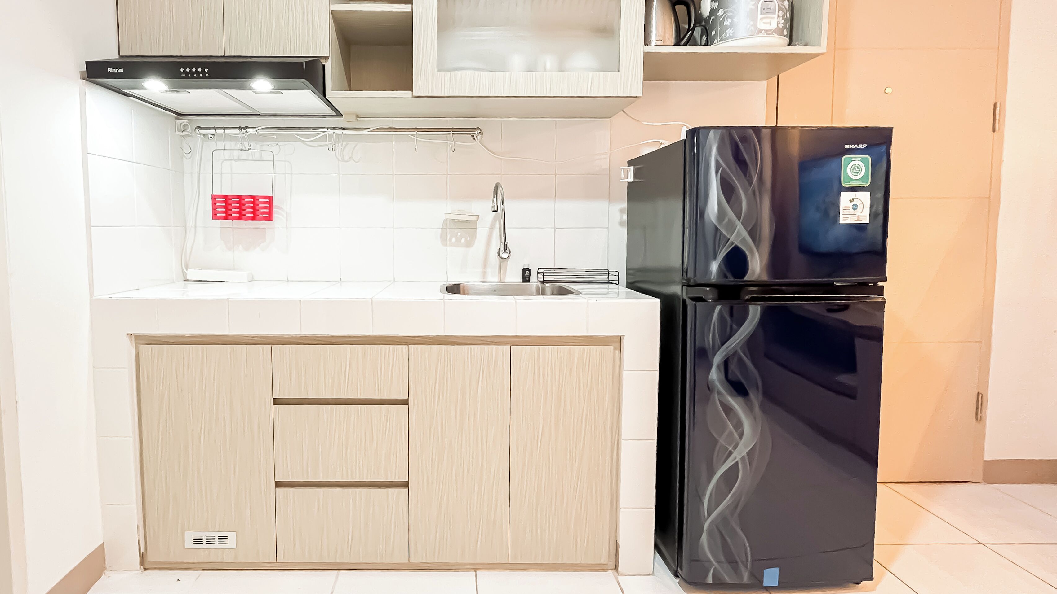 A kitchen with a black refrigerator, a sink, and wooden cabinets.