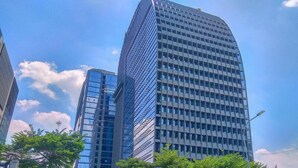 A modern high-rise building with a glass facade, surrounded by other buildings and trees. - Well Designed 1BR Apartment L'Avenue Pancoran (Jakarta)