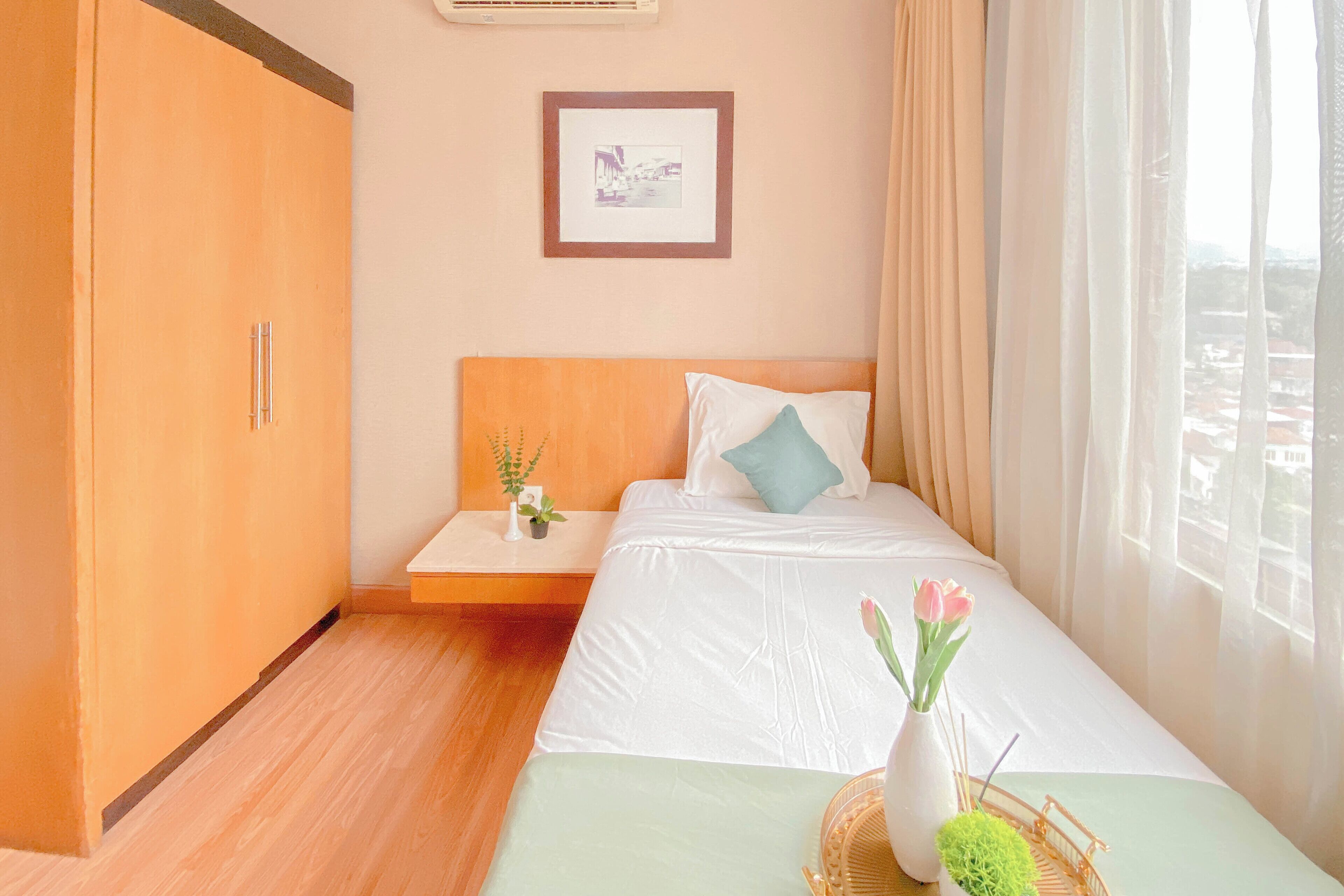 Ein Hotelzimmer mit Bett, Nachttisch, einem gerahmten Bild an der Wand und einem Fenster mit Vorhängen.
