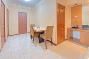 Une chambre d’hôtel équipée d’une table à manger, de chaises, d’un coin cuisine et d’une porte.