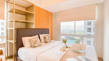 A modern bedroom with a large bed, built-in shelving, and a city view through the window.