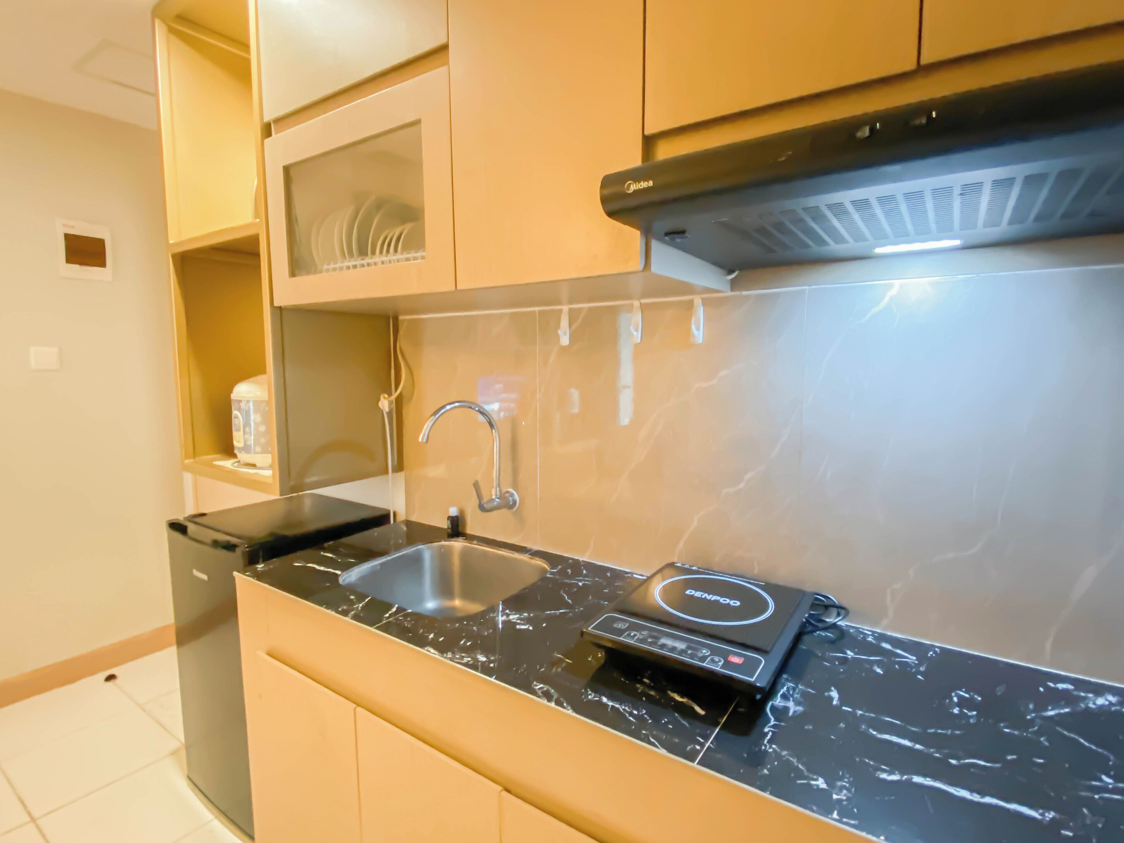 A modern kitchen with a black countertop, stainless steel sink, and a built-in oven.