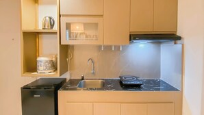 A compact kitchen with a built-in microwave, a sink, and a small refrigerator. - Stunning and Well Designed 2BR at Tokyo Riverside PIK 2 Apartment (Teluknaga)