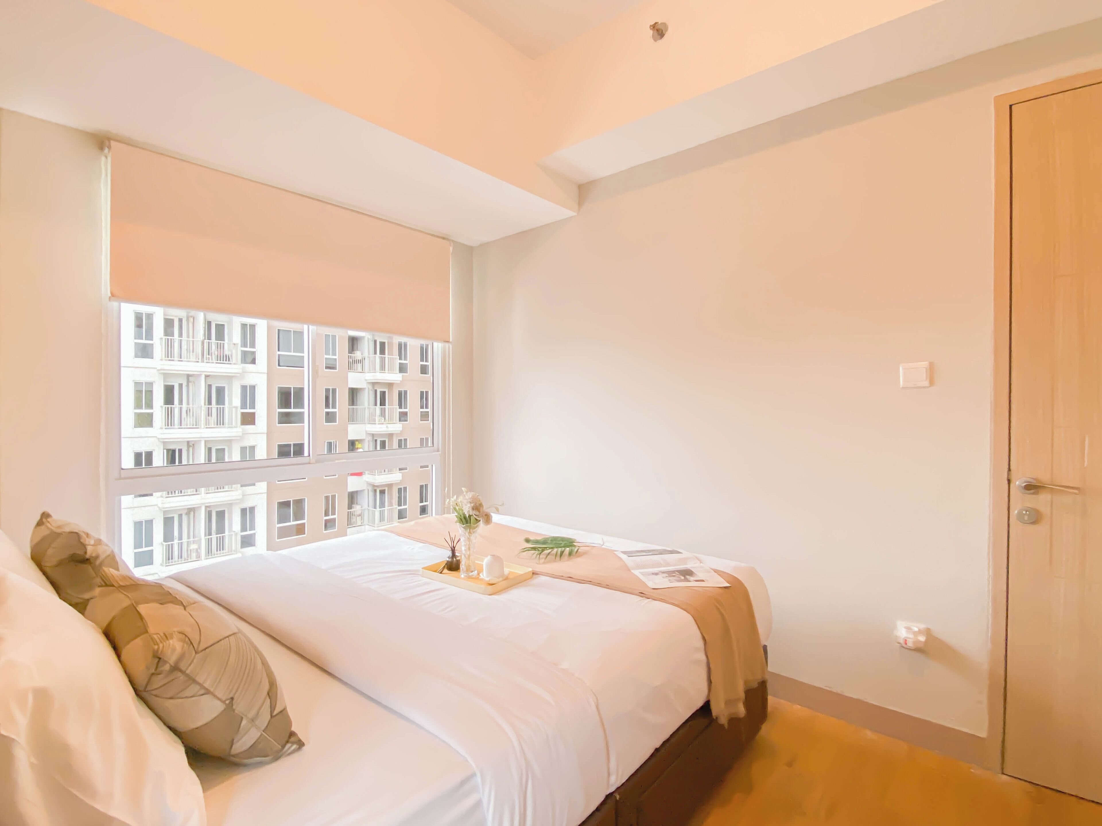 Une chambre avec une grande fenêtre, un lit, une table de chevet et une armoire.