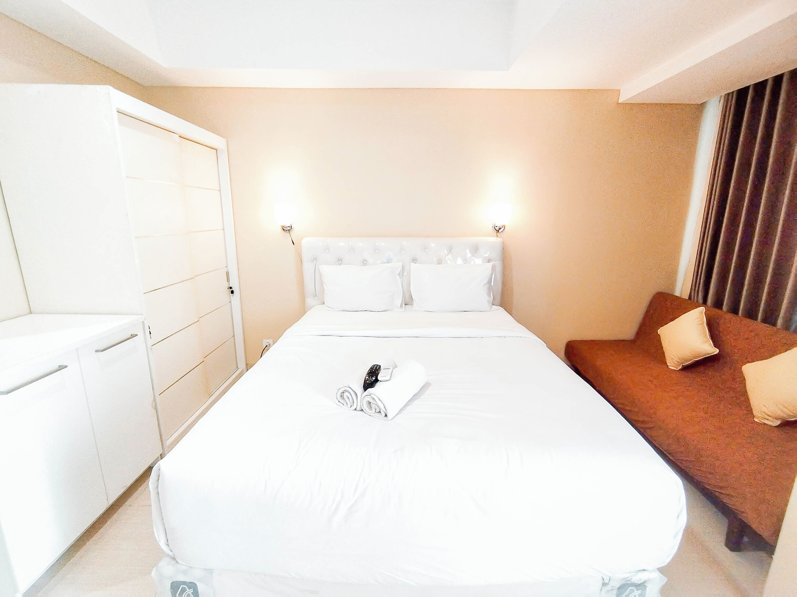A hotel room with a bed, a nightstand, a wardrobe, and a brown sofa.