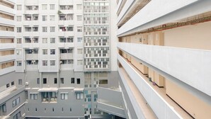 Ein mehrstöckiges Gebäude mit zeitgenössischer Architektur, mit Balkonen und einem zentralen Atrium.