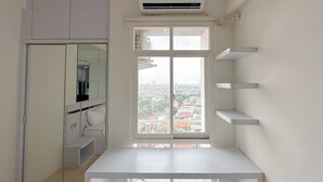 A compact room with a window, a white table, and a built-in wardrobe. - Comfortable Stay and Good Place Studio at Bale Hinggil Apartment (Surabaya)