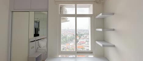 Een kleine kamer met raam, een witte tafel en een inbouwkast.