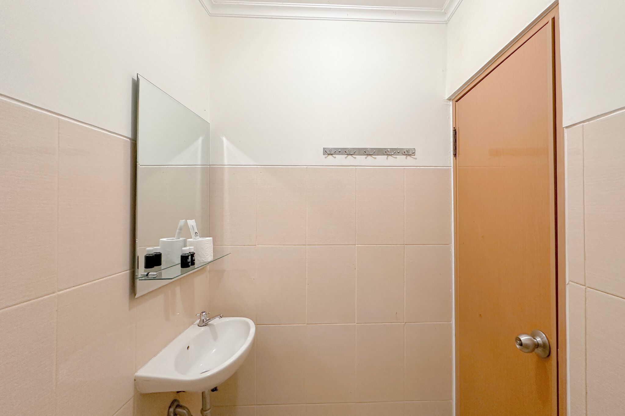 A small bathroom with a sink, mirror, and a wooden door.