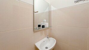 A bathroom with a white sink, a glass shelf with toiletries, and a mirror. - Comfortable Stay and Good Place Studio at Bale Hinggil Apartment (Surabaya)