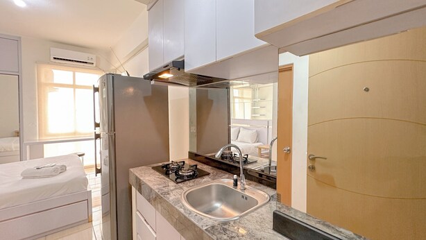 A modern kitchen with a stainless steel refrigerator, a gas stove, and a sink. - Comfortable Stay and Good Place Studio at Bale Hinggil Apartment (Surabaya)