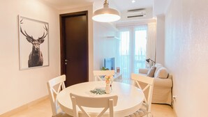 A dining area with a round table, white chairs, and a pendant light. There is a framed picture of a deer on the wall.