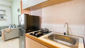 Eine kleine Küche mit Gaskochfeld, Spüle aus Edelstahl und Kühlschrank.