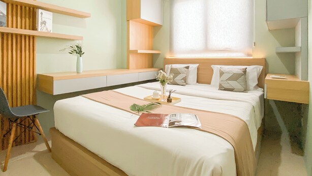 Ein modernes Schlafzimmer mit einem Bett, Nachttischen, einem Sessel und integrierten Regalen.