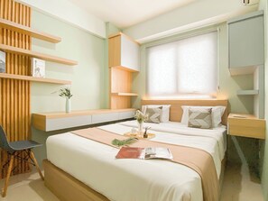 A modern bedroom with a bed, bedside tables, a chair, and built-in shelving. - Best Place and Homey 2BR at Titanium Square Apartment (Jakarta)