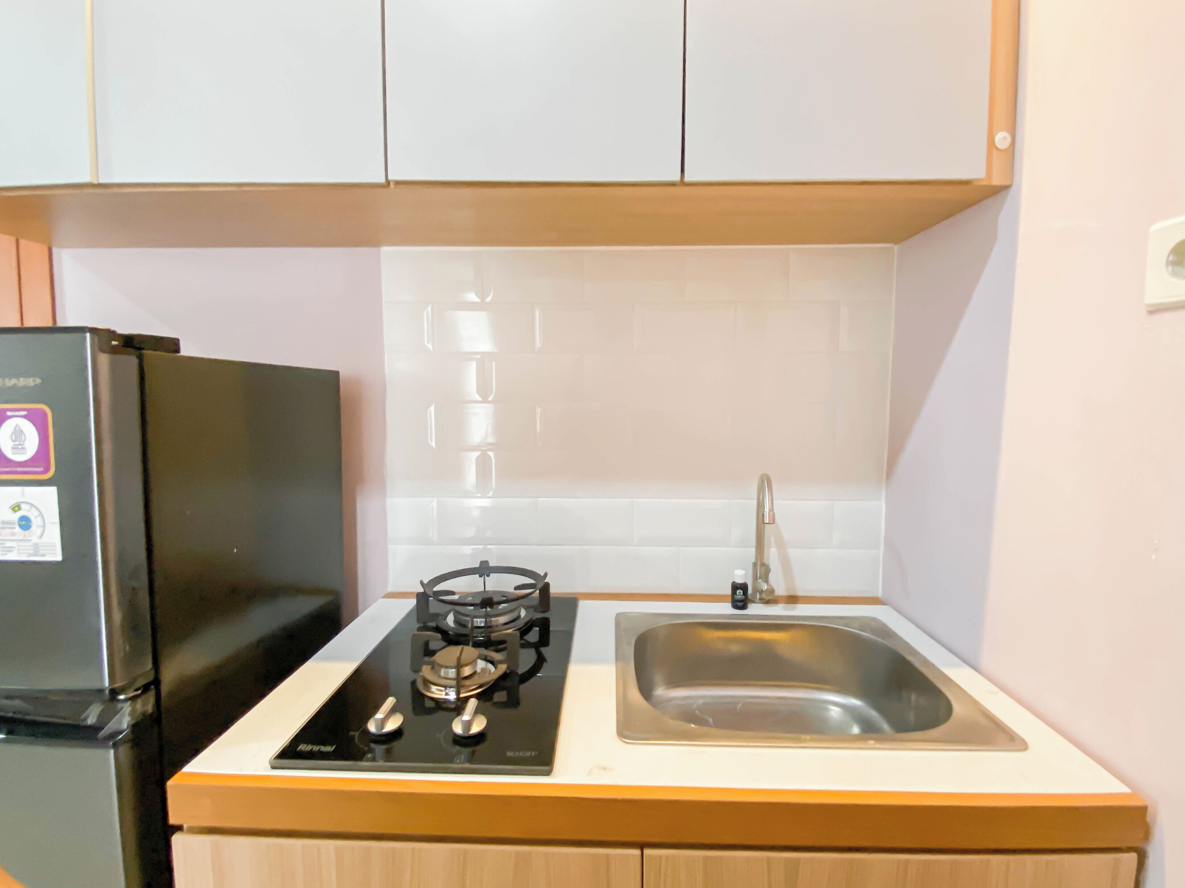 Une cuisine avec un réfrigérateur noir, une cuisinière à gaz et un évier en acier inoxydable.