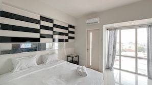 A hotel room with a large bed, a checkered wall design, a small side table, and a large window with curtains. - Minimalist and Cozy Studio at The Square Surabaya Apartment (Surabaya)