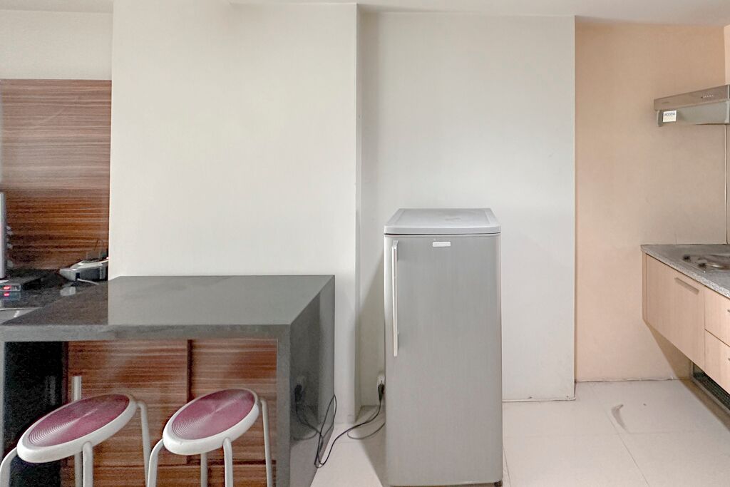 Una cucina compatta con frigorifero, due sgabelli da bar e una parete decorativa in legno.