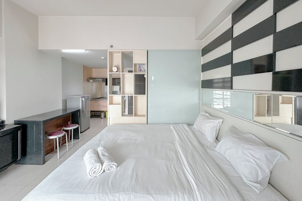 Quarto de hotel moderno com uma cama grande, uma kitchenette e uma casa de banho com chuveiro e sanita.