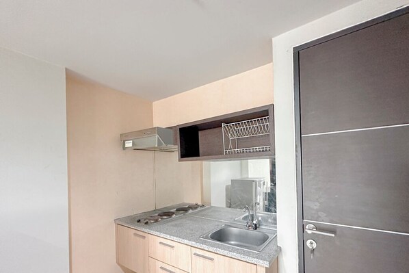 A compact kitchen with a granite countertop, stainless steel sink, and a microwave.