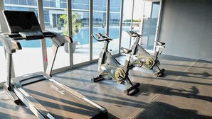 A gym with treadmills and stationary bikes, large windows, and a modern interior. - Minimalist and Cozy Studio at The Square Surabaya Apartment (Surabaya)