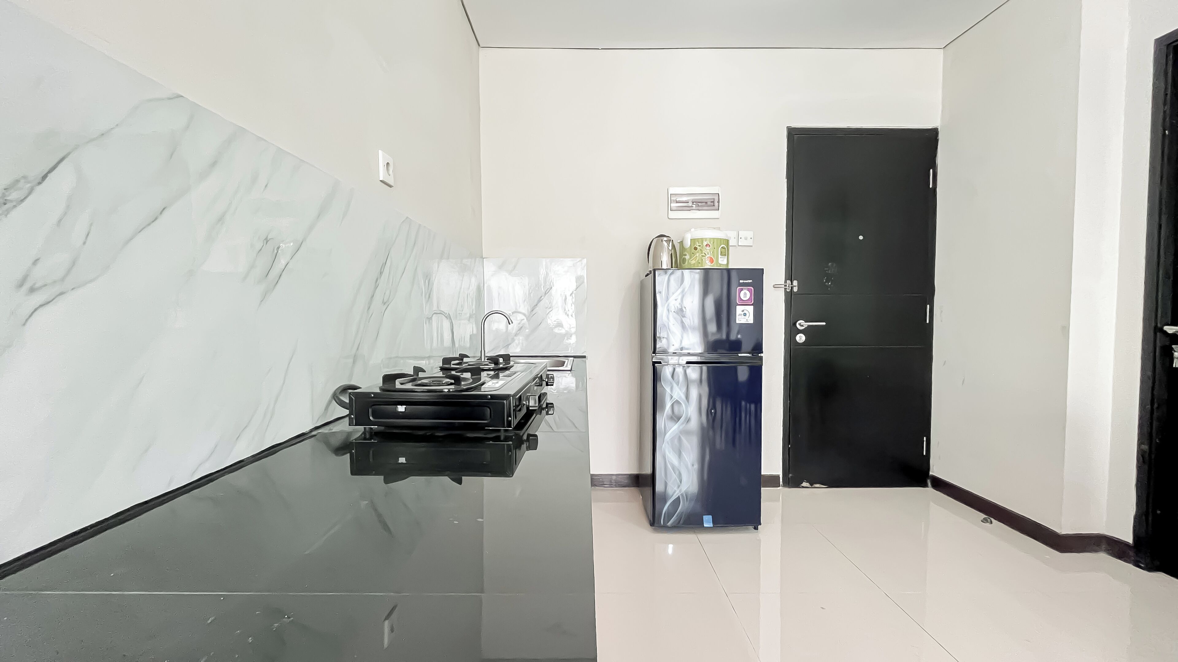 A kitchen with a marble backsplash, a black refrigerator, and a black stove.