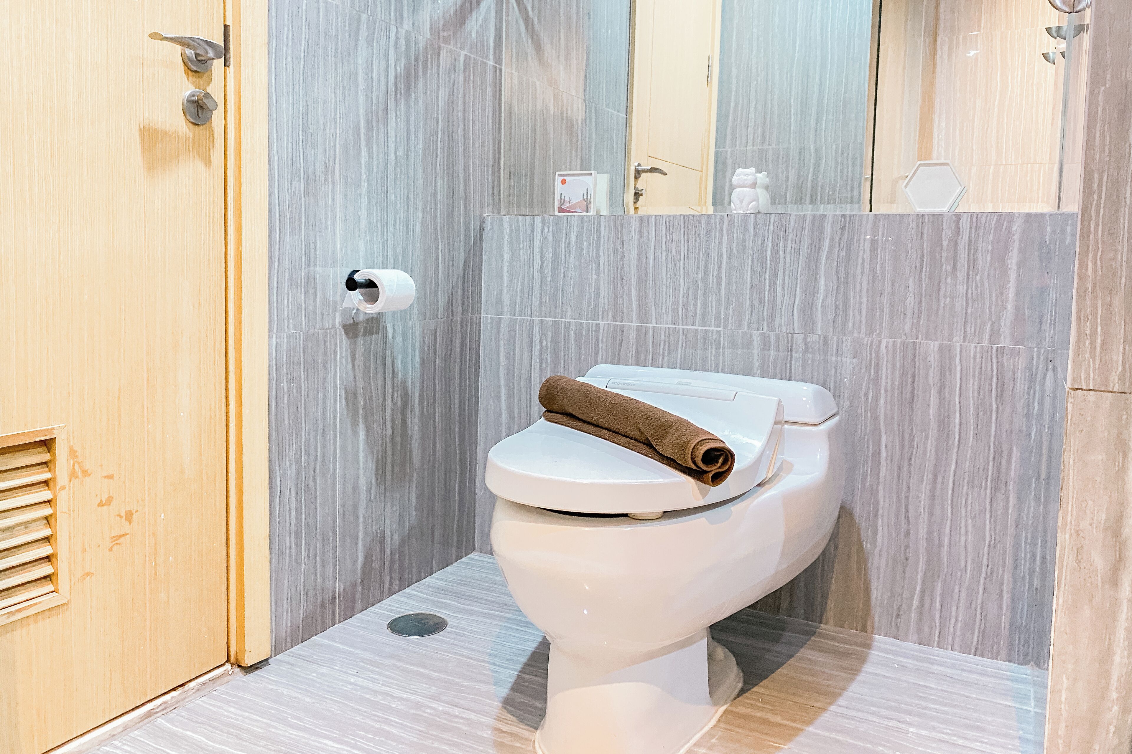 A bathroom with a toilet, a towel, and a toilet paper holder.