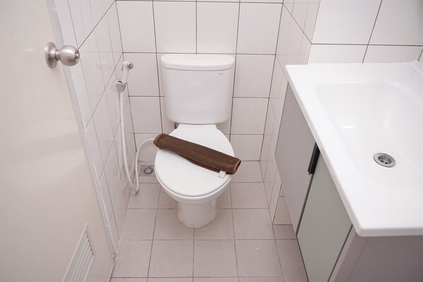 A bathroom with a toilet, a shower, and a sink.