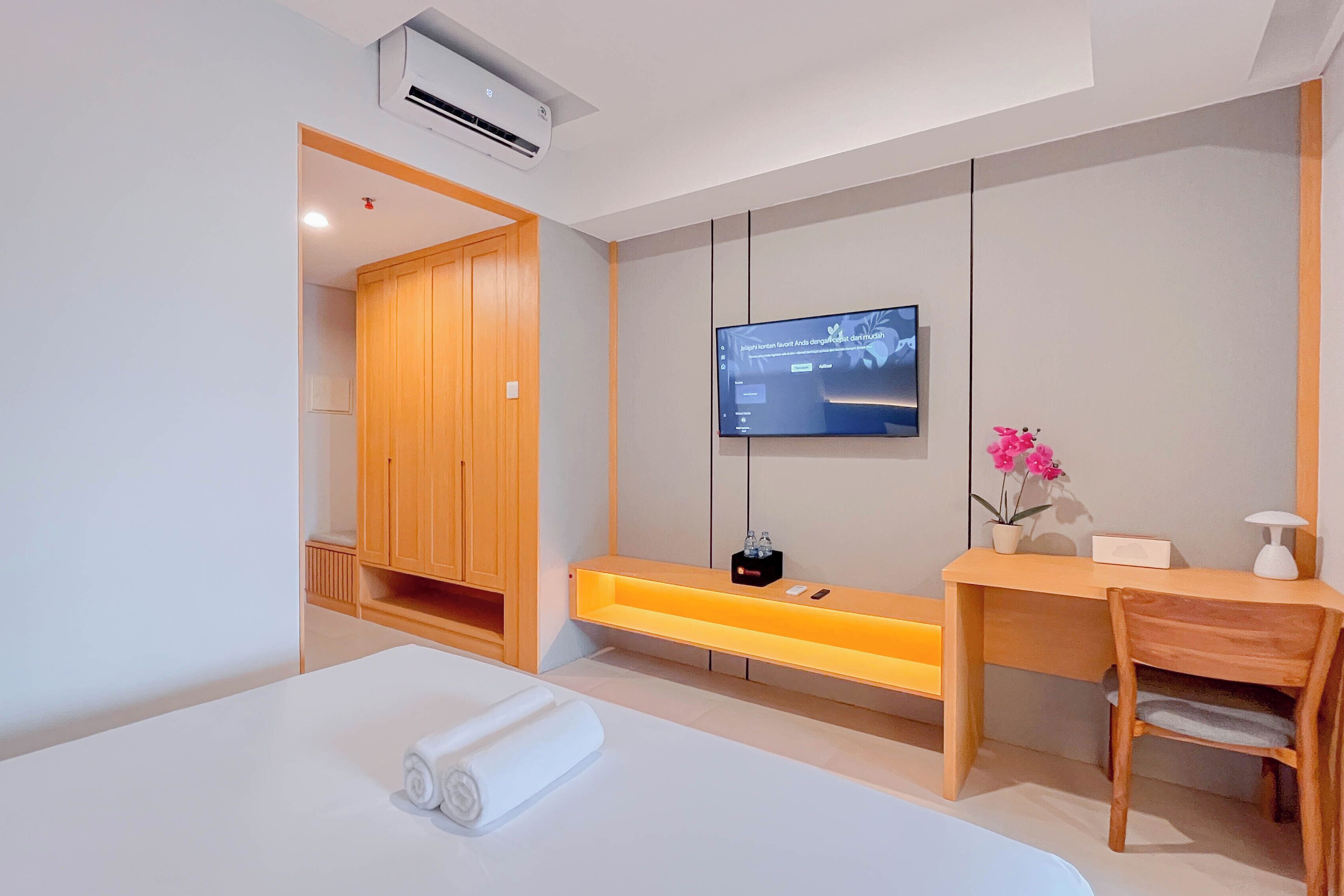 A modern hotel room with a bed, a desk, a TV, and a wardrobe.